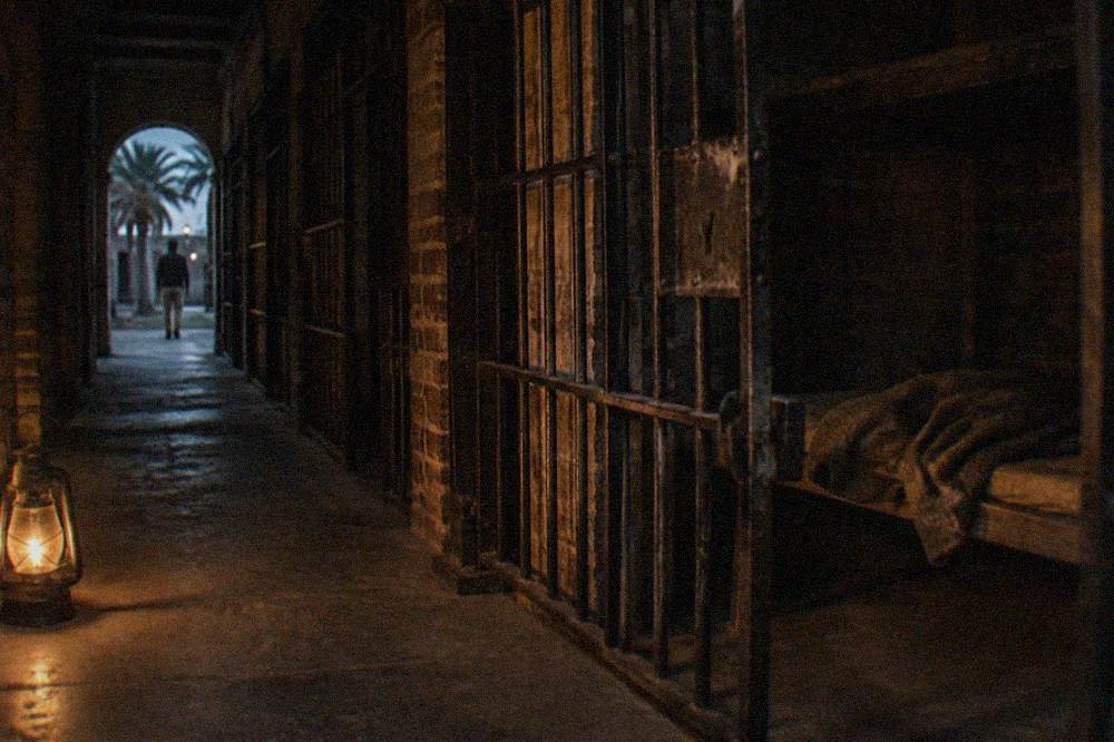 Historic jail corridor at night lit by a single lantern