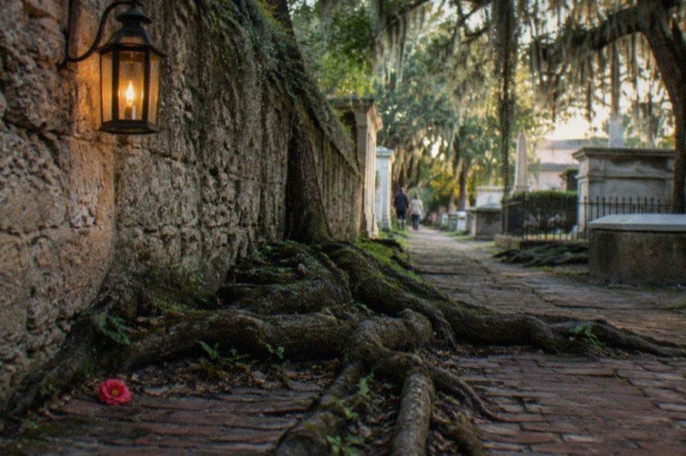 Night view of a centuries-old coquina stone wall lit by lantern light along a downtown street