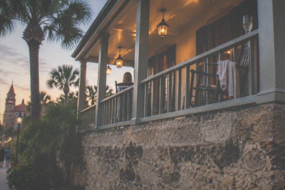 Ornate historic hotel porch with rocking chairs and warm lamplight in the evening