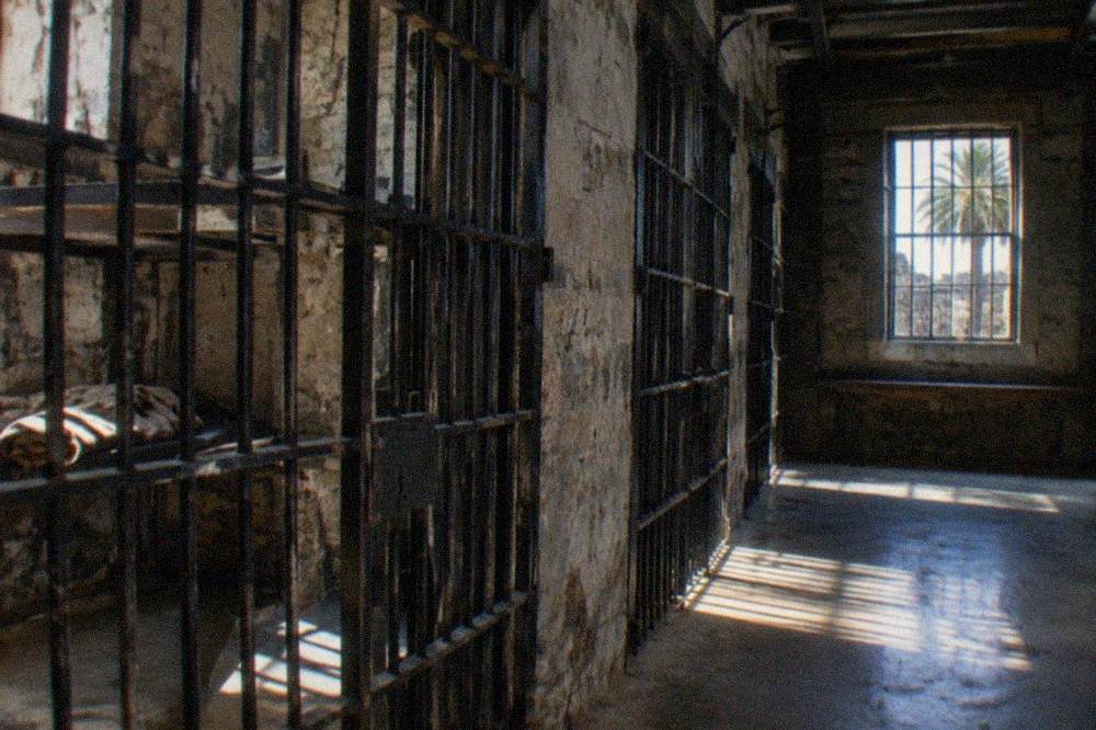 Dimly lit iron cell block inside a historic stone jail building