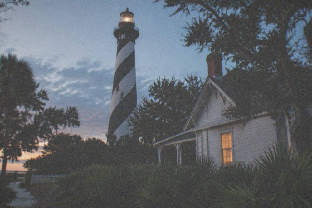 The striped St. Augustine Lighthouse tower against an evening sky
