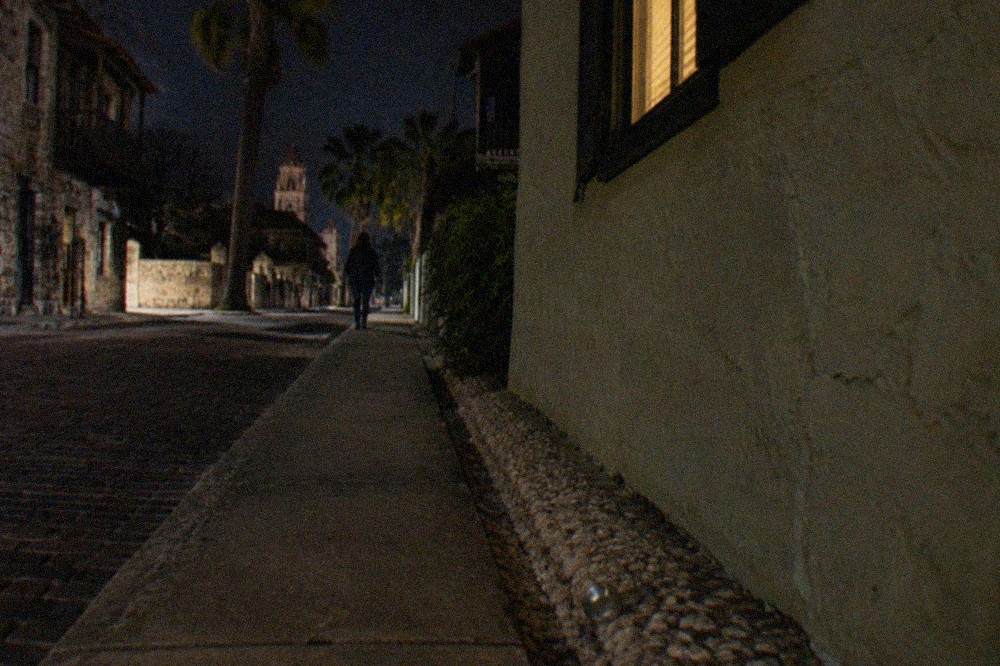 A dimly lit cobblestone lane between old coquina buildings at night