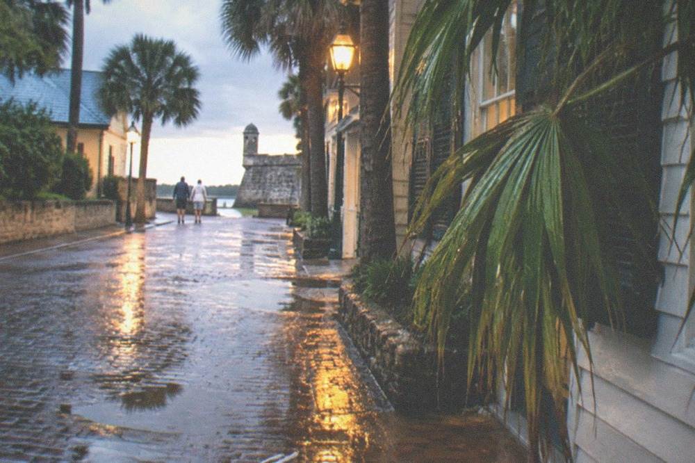 Wet cobblestone street reflecting warm lamplight after an evening rain shower