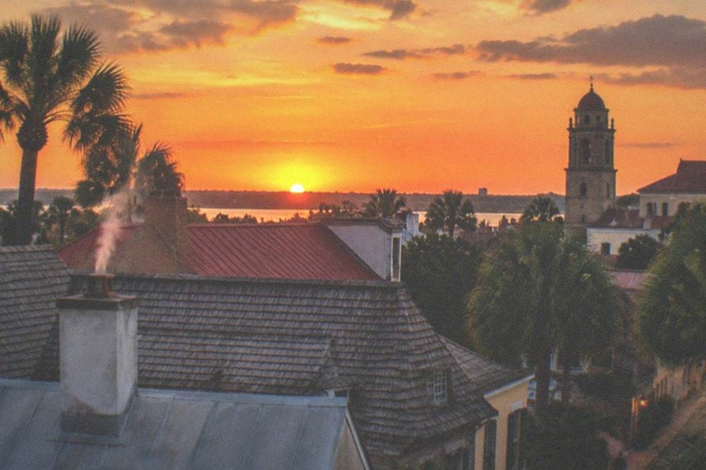 A deep orange twilight sky over silhouetted rooftops and a distant tower