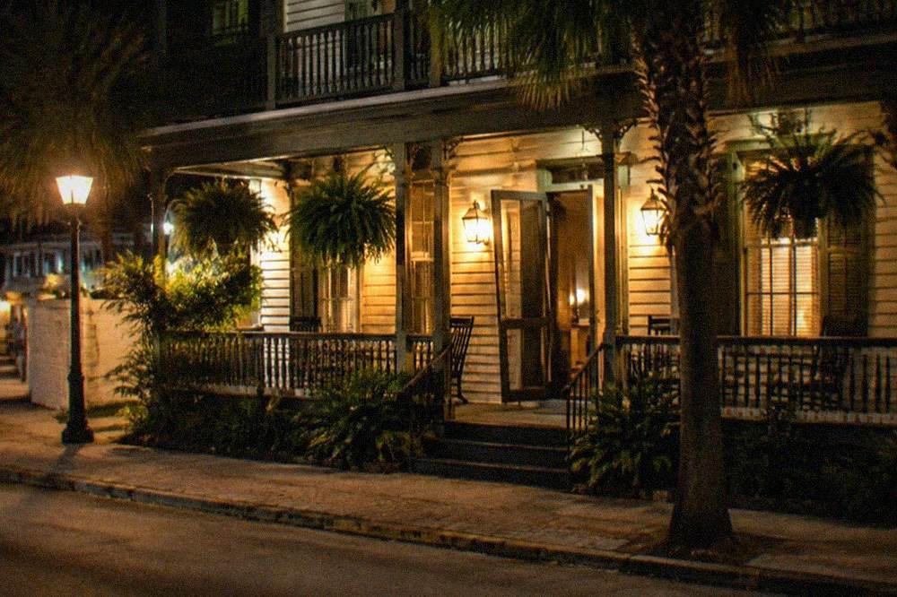 A historic inn facade at night lit by warm lamps with a wooden porch