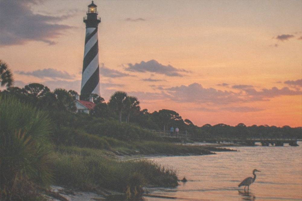 The striped lighthouse tower against a dusk sky over the water