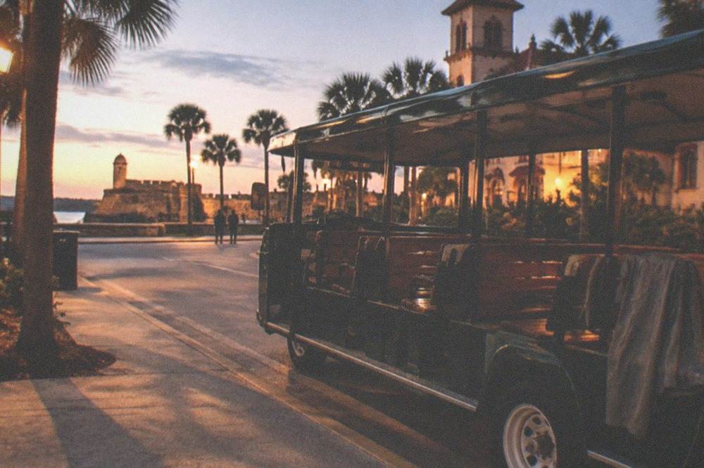An open tour trolley parked on a lamplit St. Augustine street