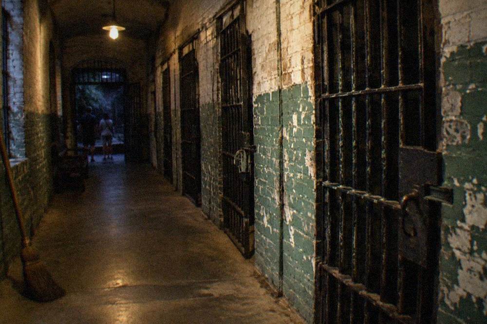 Dimly lit jail corridor with iron cell doors at night
